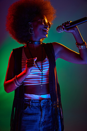 Soulful performance. Young, beautiful African-American woman singing in neon light against gradient background. Concept of art, music, hobby, classical music and modern lifestyle. Ad
