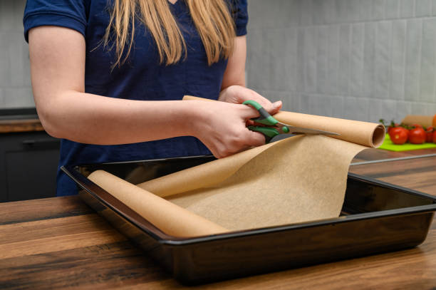 istock Line a baking tray with baking paper and cut the roll with scissors 2150086942