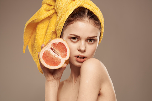 Woman with a towel on her head grapefruit in her hands health vitamins bared shoulders. High quality photo