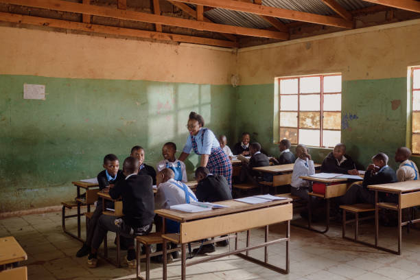 istock Female Teacher holds group discussion with high school students wearing school uniform in a rural school in Africa 2150088066