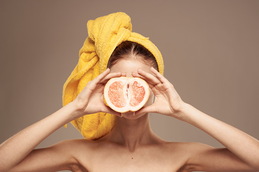 Woman with a towel on her head grapefruit in her hands health vitamins bared shoulders. High quality photo