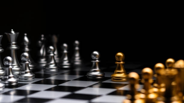 istock Chessboard perspective, silver versus golden pieces. 2150088336