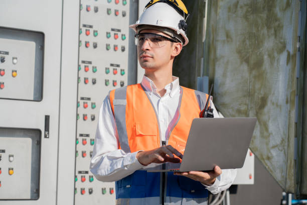 istock Portrait Asia male engineer in protective workwear is checking a electrical control cabinet or circuit electric control button at rooftop building 2150088538