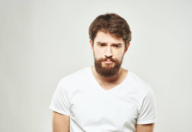 istock Guy in a white T-shirt on a light background emotions sad face cropped view 2150090382
