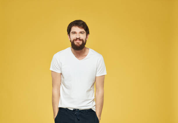 istock A man with a beard is gesturing with his hands on a yellow background and dark trousers are a model 2150091171