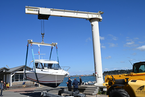 Dinard, France, april 18, 2024 : Lifting a motor boat with a harbor crane for launching in the Dinard marina