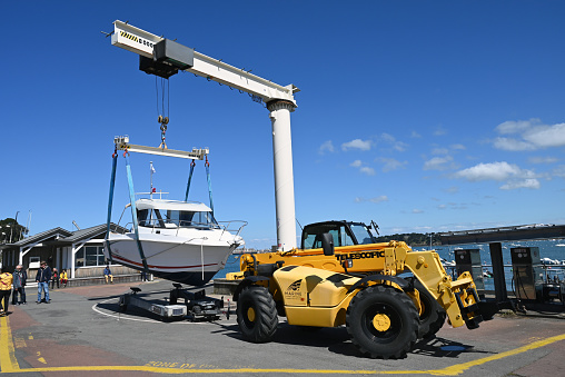 Dinard, France, april 18, 2024 : Lifting a motor boat with a harbor crane for launching in the Dinard marina