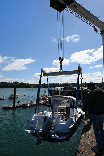 Dinard, France, april 18, 2024 : Motor boat winched with a port crane for launching in the Dinard marina