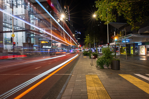 Auckland, New Zealand - July 01 2023: Long exposure image of Queen Street at night with bus light trails passing through the street.