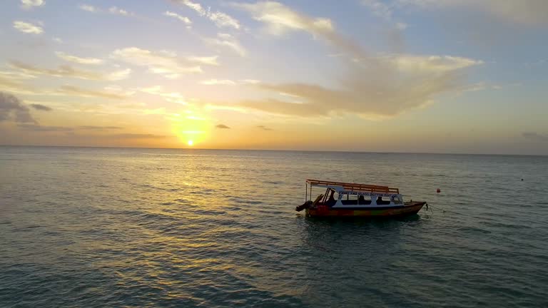 Glass bottom boat Tobago Sunset sailing on calm ocean water. Aerial drone pull-back shot