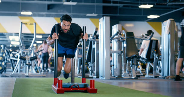 istock Man, gym and push sled in workout for challenge in exercise with strong body builder. Healthy, training and person with resilience moving machine or weightlifting equipment for fitness and wellness 2150096362