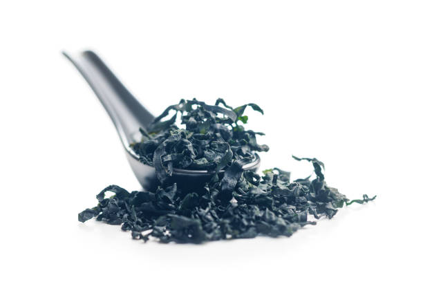 Dried wakame seaweed in spoon isolated on a white background.