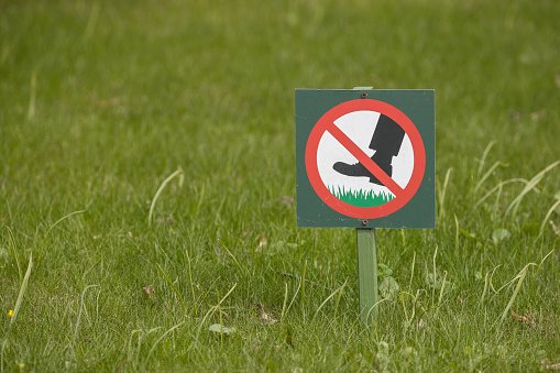 A sign in the park forbidding walking on lawns with grass