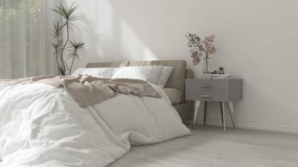 istock Modern, minimal white bedroom with beige bed, gray side table, dracaena tree in sunlight from window with sheer curtain 2150101115
