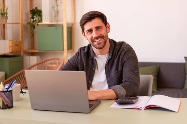 istock Smiling man working on laptop in home office 2150101756