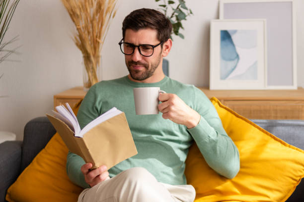 istock Man enjoying book and coffee on sofa 2150101807