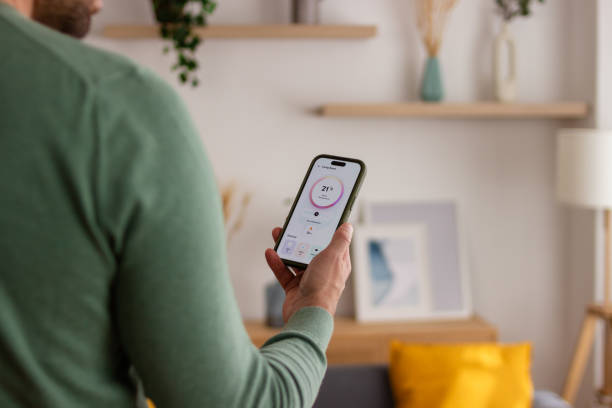 istock Man controlling smart thermostat from smartphone 2150101931