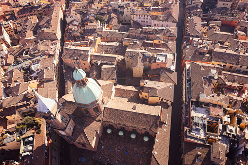 An aerial view of Bologna historic city center, highlighting the domes of the Church of Saints Bartholomew and Cajetan surrounded by narrow city streets and densely packed rooftops