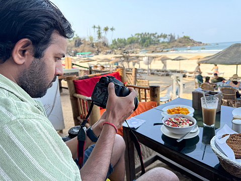 Stock photo showing a close-up view of a behind the scenes food photography of healthy smoothie bowl breakfast served at in an al fresco dining area of a beach restaurant.