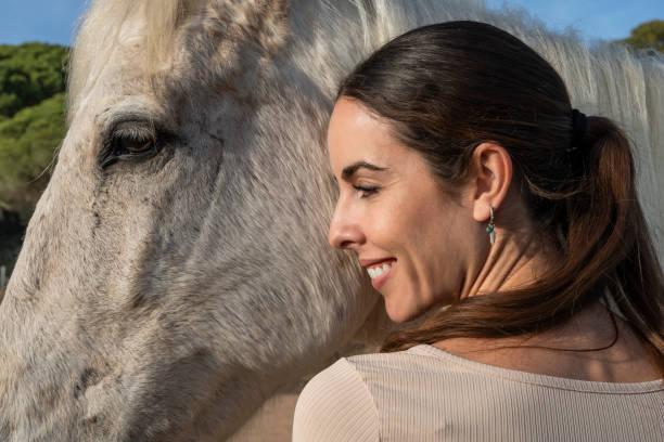 istock Woman smiling beside white horse's face. 2150104649