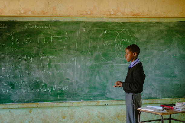 istock African Schoolboy Learner in front of chalkboard with mathematics in a rural school classroom 2150105208