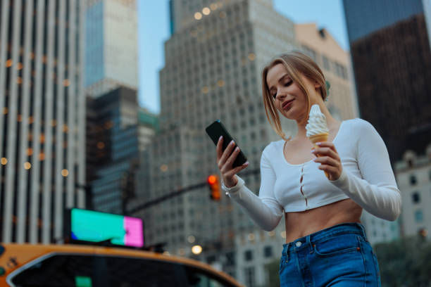 istock Woman browsing phone with ice cream in city 2150106705