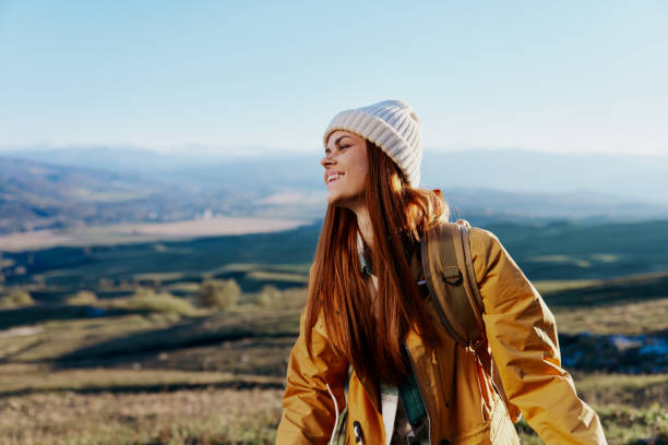 istock woman in a yellow jacket in a hat backpack travel mountains relaxation 2150108913