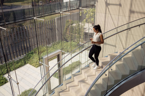 istock Smiling Thai woman using cell phone on the stairs. 2150111006