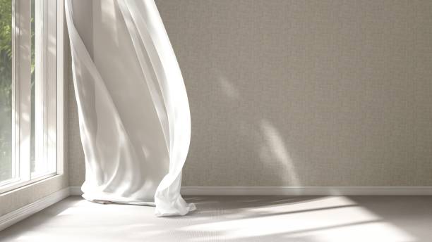 istock Empty beige wall room in sunlight from window, blowing white sheer, brown blackout curtain tree shadow on baseboard, carpet floor 2150111054