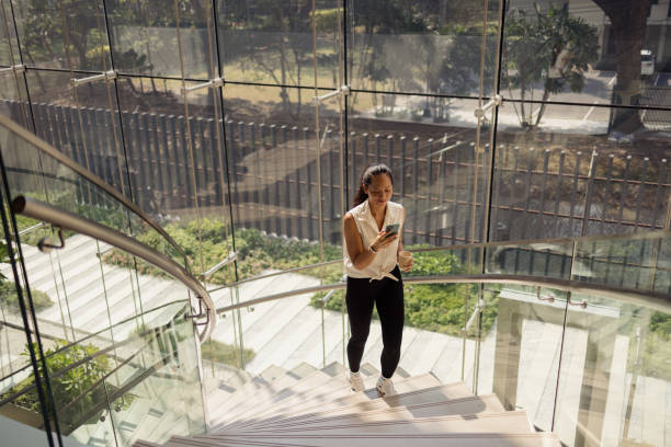 istock Above view of Thai woman using phone while walking up the stairs. 2150112464