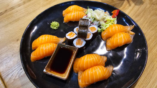 A wooden table showcases a black plate filled with sushi topped with sauce, a delightful seafood dish perfect for any cuisine enthusiast Hanover Germany
