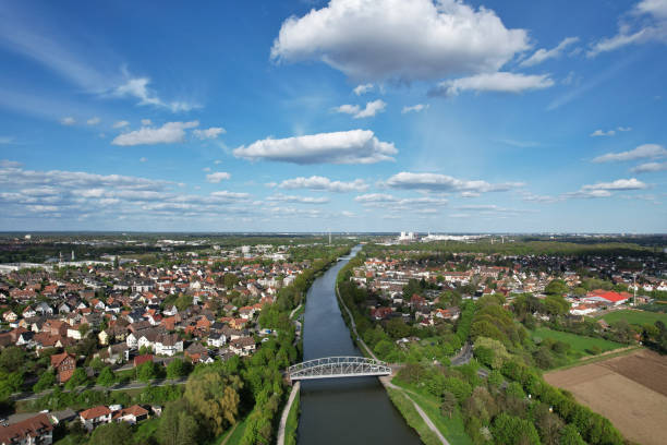 istock River meanders through green landscape with houses and trees, under a cloudy sky Mittellandkanal Hanover 2150115690