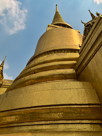 Stock photo showing close-up view of the golden exterior decoration of the at Temple of the Emerald Buddha (Wat Phra Kaeo), part of the Royal Grand Palace complex, Bangkok, Thailand.
