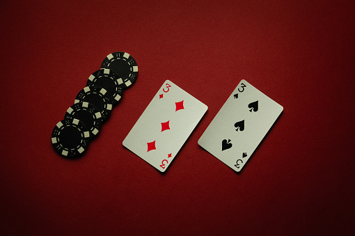 Luck in a poker card game with a winning one pair combination. Playing cards and chips are laid out in a club on a red table.