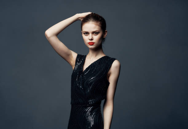 istock Charming lady in a black dress with bare shoulders on a gray background Copy Space 2150120380