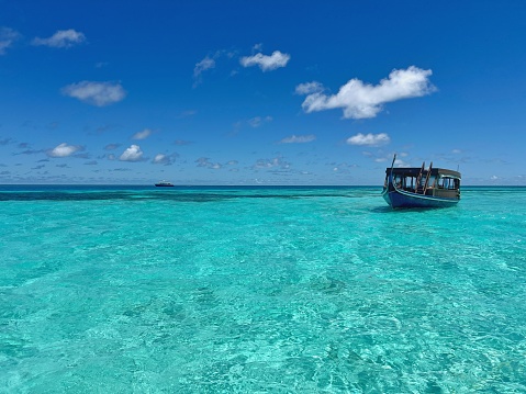 A single boat is docking on the cristal clear water in the Maldives oceans