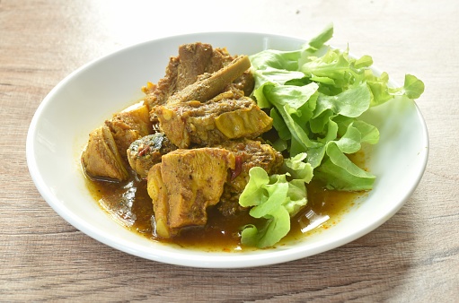 spicy fried pork bone with curry with fresh green oak salad on plate