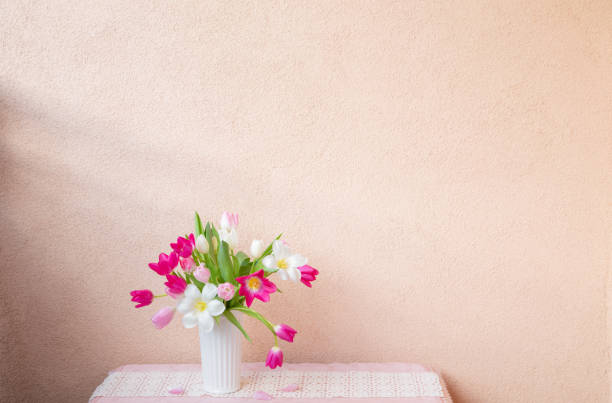 tulips in vase on table on background wall