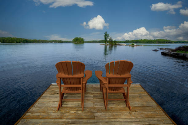 istock Two yellow Adirondack chairs on a wooden dock 2150125855