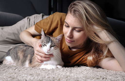 Pretty blond woman playing with her happy cat at home