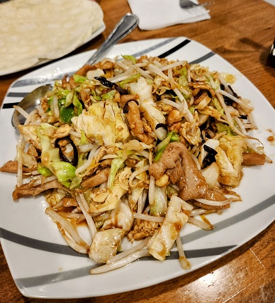 Close-up of a plate of Moo Shoo chicken with mixed vegetables including bean sprouts and cabbage.