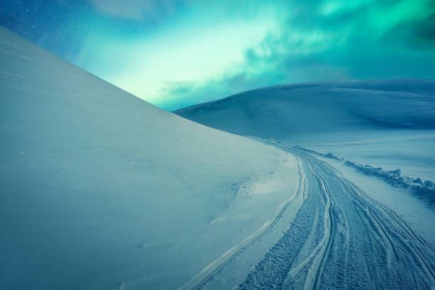Fantastic Aurora borealis, Northern lights glowing over snow covered mountain on glacier summit in Arctic Circle