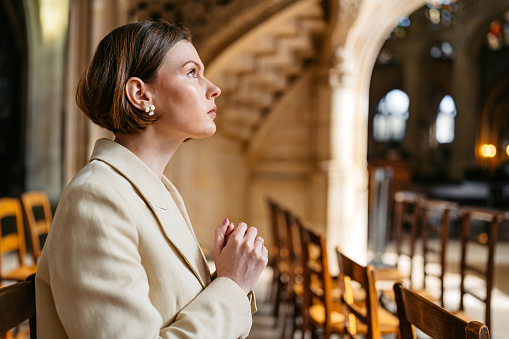 Beautiful young woman praying in the church in Paris.