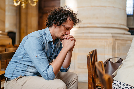 Handsome young man praying in the church in Paris.