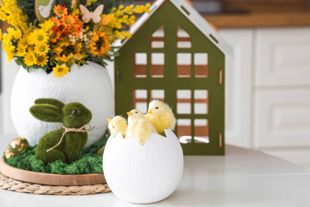 istock A spring bouquet, yellow little chickens in a large egg and Easter eggs with a golden pattern on the table. In the background is a white Scandinavian-style kitchen. Easter decor in the house. 2150131853