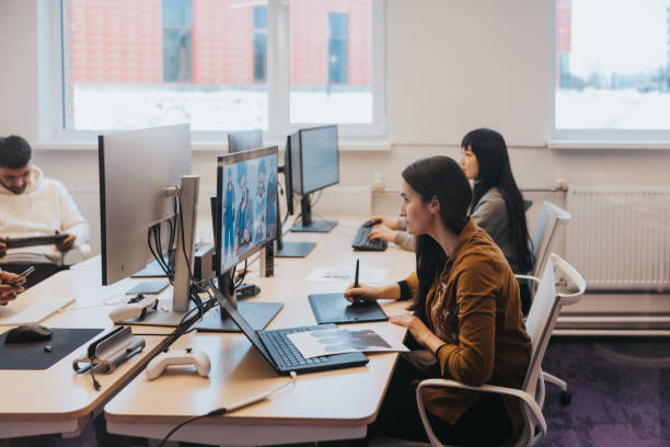istock Together at their desks, gaming developers work in harmony, their screens filled with the intricate details of their latest video game creation 2150132058