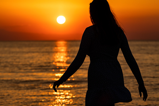 Silhouette of carefree woman on the beach at sunset