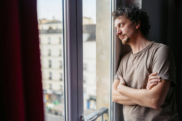 istock Depressed Young Man Looking Out The Window In Paris 2150132449