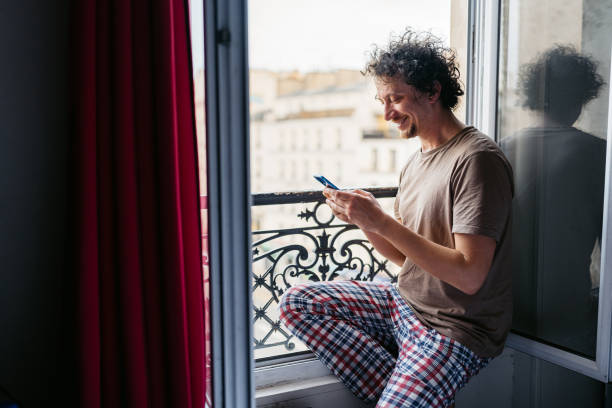 istock Young Man Using Phone By The Window In Paris 2150132495