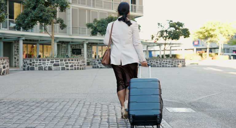 Business woman, luggage and walking in city for travel opportunity, immigration or career trip. Back of professional person or entrepreneur with suitcase for airport, hotel or journey to location